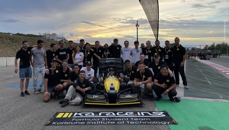 Gruppenfoto KA-RaceIng-Team der Formula Student mit Rennwagen