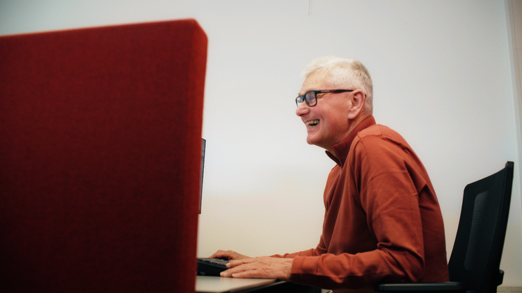 Richard van Aalten lachend, werkend achter de computer.