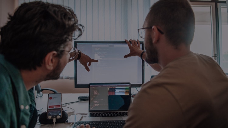 Twee engineers werkend achter een computer. Een van de engineers wijst naar het scherm.