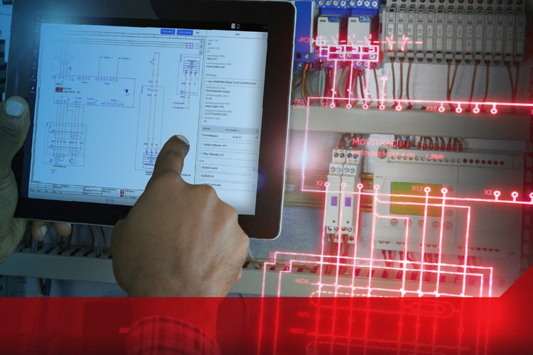 A tablet computer displaying electrical schematics next to an open electrical control panel